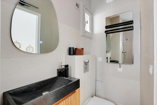 une salle de bain avec un lavabo, des toilettes et un miroir dans l'établissement 2 pièces au coeur de Montmartre - proche Sacré Coeur, à Paris
