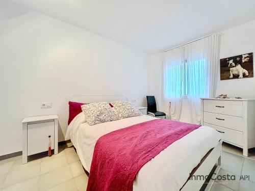 a white bedroom with a bed and a dresser at El Racó del Sol in L'Estartit