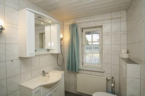 a bathroom with a sink and a toilet and a window at Ferienhaus Strandlatscher Ferienwohnung 02 in Wiek auf Rügen 