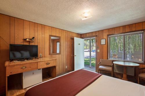 a bedroom with a bed and a television and a table at Birch Glen Hotel in Cascade
