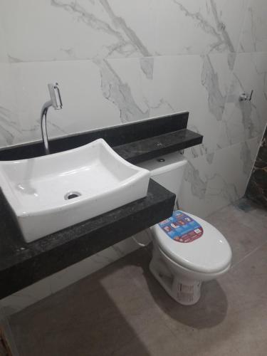 a bathroom with a white sink and a toilet at COP 30 Casa com 3 quartos sendo 1 suite 4 banheiros sala cozinha e garagem in Ananindeua