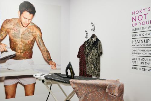 a man with tattoos on his torso standing next to a table at Moxy Amsterdam Schiphol Airport in Hoofddorp