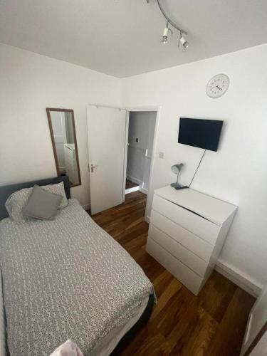a bedroom with a bed and a dresser with a tv at Family Home Stay in Thornton Heath