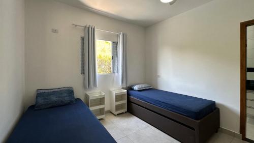 a bedroom with two beds and a window at Casa aconchegante perto da Praia de Massaguacu in Massaguassu