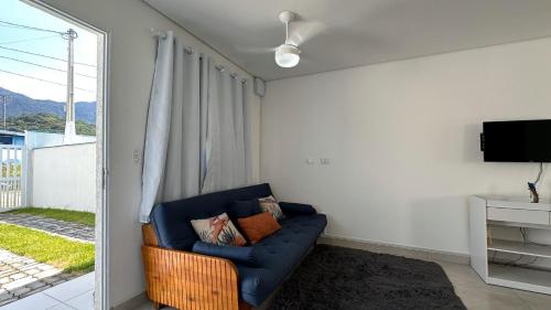 a living room with a blue couch and a tv at Casa aconchegante perto da Praia de Massaguacu in Massaguassu