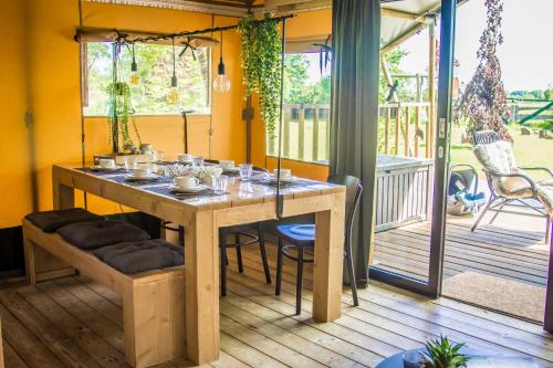 a dining room table with chairs on a porch at Zorgcamping De Ruif De Peppelhoeve in Stoutenburg