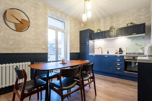 une cuisine avec des placards bleus et une table et des chaises en bois dans l'établissement Le Vintage, à Metz
