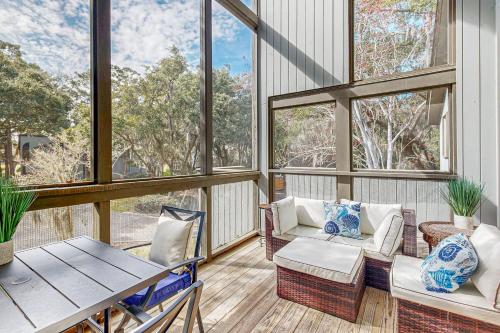 a screened in porch with a table and chairs and windows at Parkside 4518 in Kiawah Island
