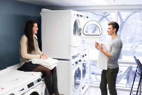 a man and a woman standing next to a washing machine at UWinnipeg Downtown Hostel in Winnipeg