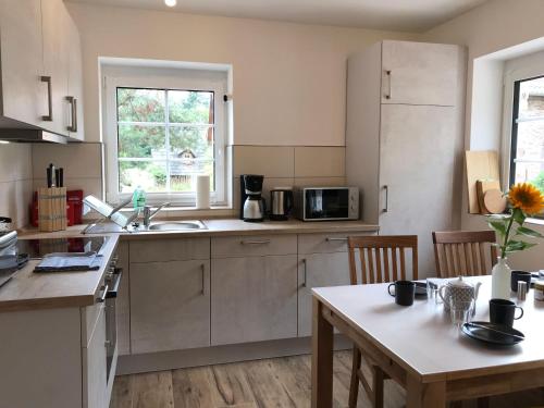 a kitchen with white cabinets and a table with a table sidx sidx sidx at Bispinger-Heidezauber-Haus-Felsenbirne in Bispingen