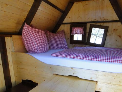 a bed in a wooden cabin with red and white pillows at Bispinger-Heidezauber-Haus-Felsenbirne in Bispingen