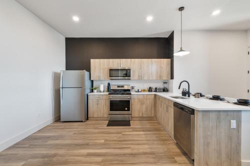 a kitchen with stainless steel appliances and wooden cabinets at 2BR, King Bd, Free Prkn, Gym, NYC View, 8min Train in East Orange