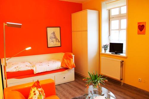 a bedroom with orange walls and a bed and a window at Hof Esterau - Appartment gelb in Heuerstorf