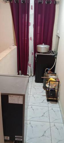 a kitchen with purple curtains and a sink and a counter at New Deal house in Yaoundé