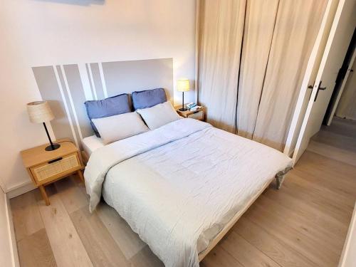 - une chambre avec un grand lit blanc aux accents bleus dans l'établissement Appartement T2 - Piscine, Tennis, Parking - À 200m des Plages et Commerces - FR-1-316-299, à Six-Fours-les-Plages