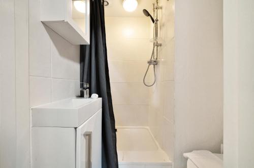 a white bathroom with a shower and a sink at Tranquil Studio Retreat in Harrow in Harrow