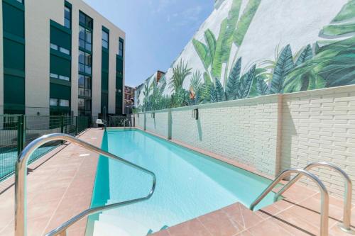 a swimming pool with a mural of palm trees on the side of a building at Aurora Stays by Charming - Parking cubierto gratis in Madrid