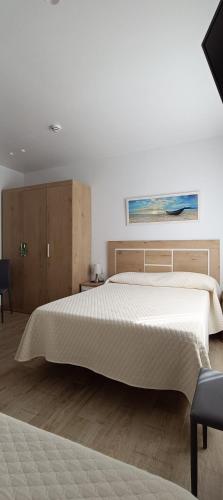a bedroom with a large white bed and wooden cabinets at Hostal Internacional in Miami Platja