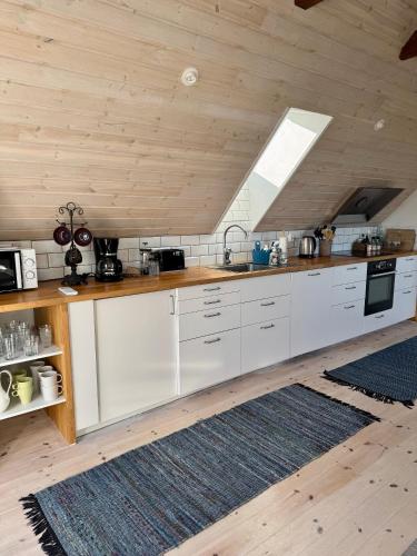 a kitchen with white cabinets and a wooden ceiling at Arnhög Farm in Borrby
