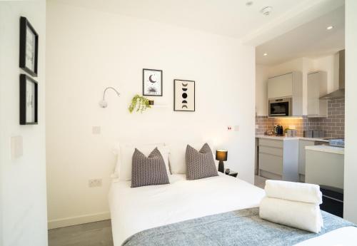 a white bedroom with a bed and a kitchen at Tranquil Studio Retreat in Harrow in Harrow