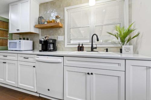 a kitchen with white cabinets and a sink and a window at Sandy Feet Getaway Spacious Coastal Retreat 3 MIn Walk to Coast in Gulfport