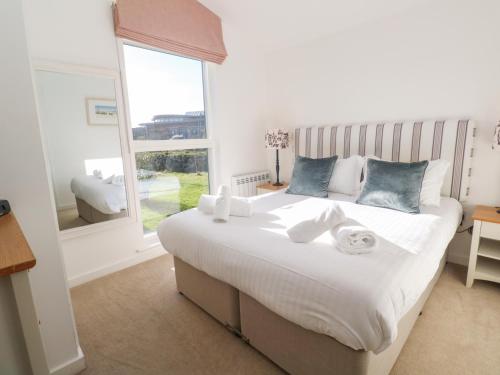 a bedroom with a large white bed with a window at Una, Lodge 77 in St Ives