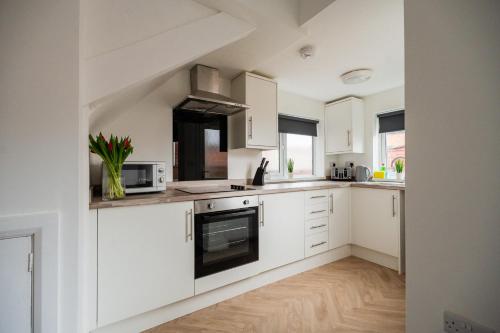 a kitchen with white cabinets and a stove top oven at Buckingham House Horizon Stays in Redcar