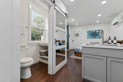 a white bathroom with a toilet and a sink at Coastal Cabana Studio - Close to beach and Mississippi City in Gulfport