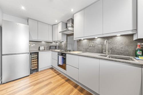 a kitchen with white cabinets and a wooden floor at Slateford 2 Bedroom Apartment - Edinburgh in Edinburgh