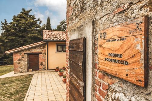 a sign on the side of a brick wall with a house at Masseria del bosco Poderuccio in Chianciano Terme