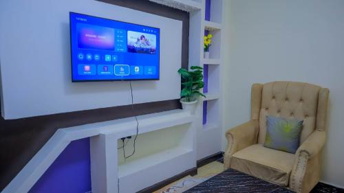 a living room with a chair and a tv on a wall at SpringStone executive apartment in Ongata Rongai 