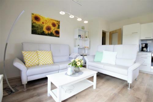 ein Wohnzimmer mit zwei weißen Sofas und einem Tisch in der Unterkunft Ferienwohnung Kube in Grömitz