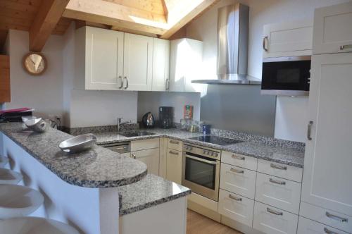 a kitchen with white cabinets and granite counter tops at Appartement ski in and ski out in Val-d'Illiez