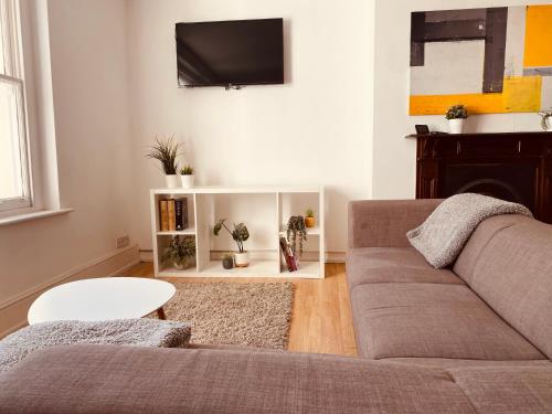 a living room with a couch and a tv on a wall at Iconic Location 3 Bed 2 Bath Flat near Regents Park in London