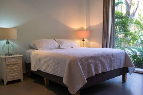 a bed in a bedroom with two lamps and a window at Casa Coastin in Nosara
