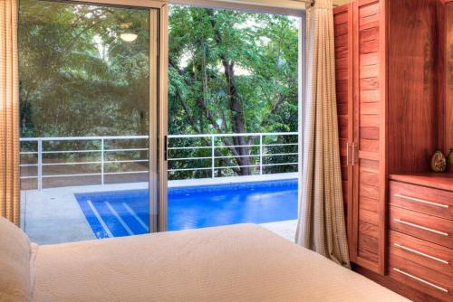 a bedroom with a view of a pool through a window at Casa Coastin in Nosara