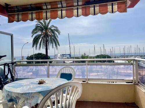 une table et des chaises sur un balcon avec un palmier dans l'établissement Studio face port et mer, à Menton