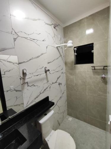 a bathroom with a toilet and a marble wall at Pousada Pai&Filho in Piranhas