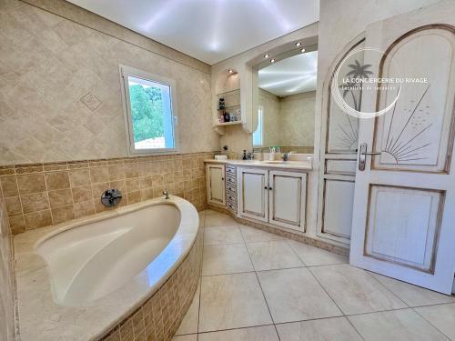 une grande salle de bain avec une baignoire et un lavabo dans l'établissement Villa Les Freesias - Grande Piscine - Vue sur Mer, à Carqueiranne