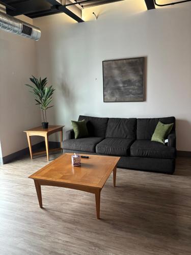 a living room with a black couch and a coffee table at New Luxury Downtown 1 Bedroom Condo 201 in Kalamazoo