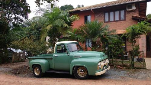 a green truck parked in front of a house at Hostel Dina & Suítes in Pomerode