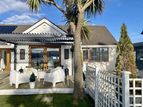 a white house with a white fence and palm trees at Seaview Cottage on the Island in Millbay