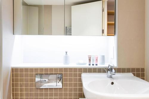 a bathroom with a sink and a mirror at Spacious & Elegant Apartments in Southbank near London Eye in London