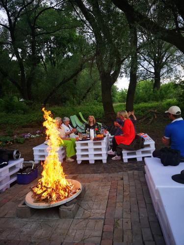 a group of people sitting around a fire pit at Pirtelė Rykštelė in Karmėlava
