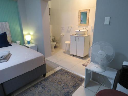 a bedroom with a bed and a bathroom with a fan at Destiny Jeffreys bay in Jeffreys Bay