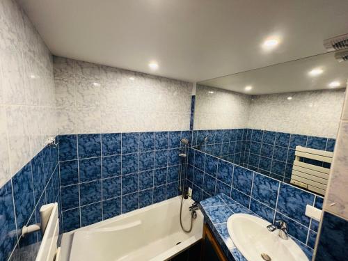 La salle de bains est pourvue de carrelage bleu, d'une baignoire et d'un lavabo. dans l'établissement T2 Proche Polygone - piscine, parking privé, fibre, à Cagnes-sur-Mer