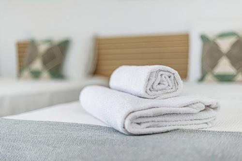 a pile of towels sitting on top of a bed at CoralMar Beachfront Apartment -Stunning Ocean Views -Algarve in Armação de Pêra