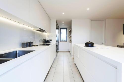 a kitchen with white counters and a sink at Spacious & Elegant Apartments in Southbank near London Eye in London