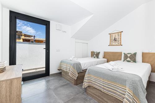 two beds in a room with a large window at CoralMar Beachfront Apartment -Stunning Ocean Views -Algarve in Armação de Pêra