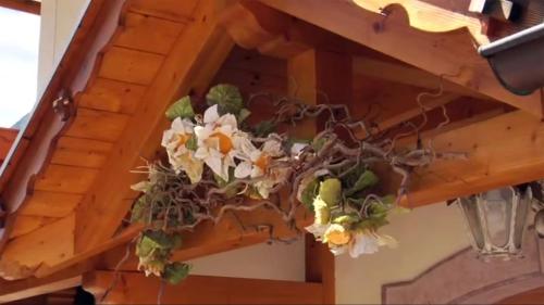 a flower basket hanging from a wooden ceiling at Hotel Olympia in Molveno